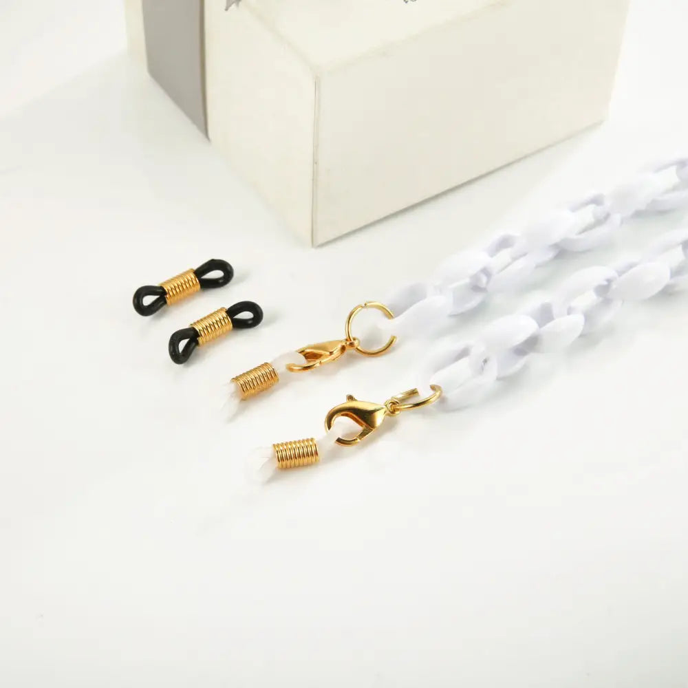 Helle weiße Brillenkette mit goldenen Karabinern und schwarzen Gummibändern