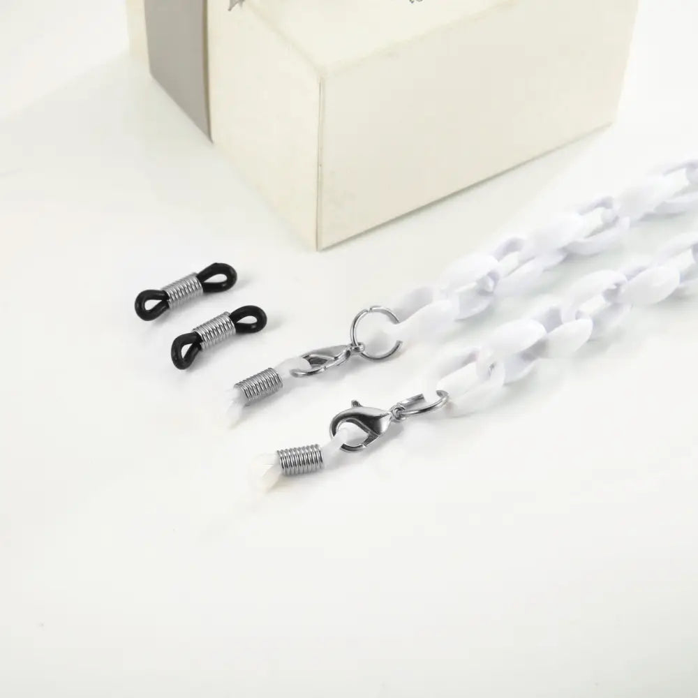 Helle weiße Brillenkette mit silbernen Haken und schwarzen Gummibändern