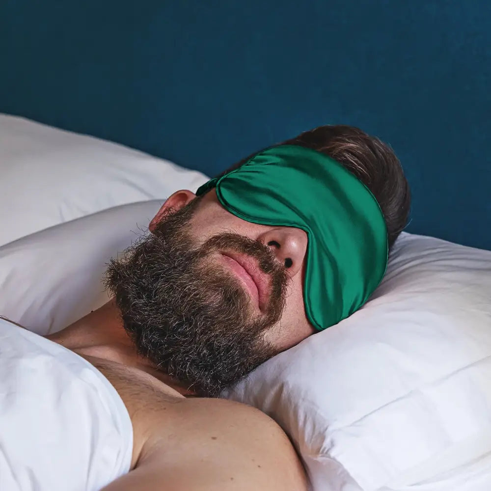 Schlafende Mann mit Dunkelgrüne Schlaf-Seidenmaske auf den Augen