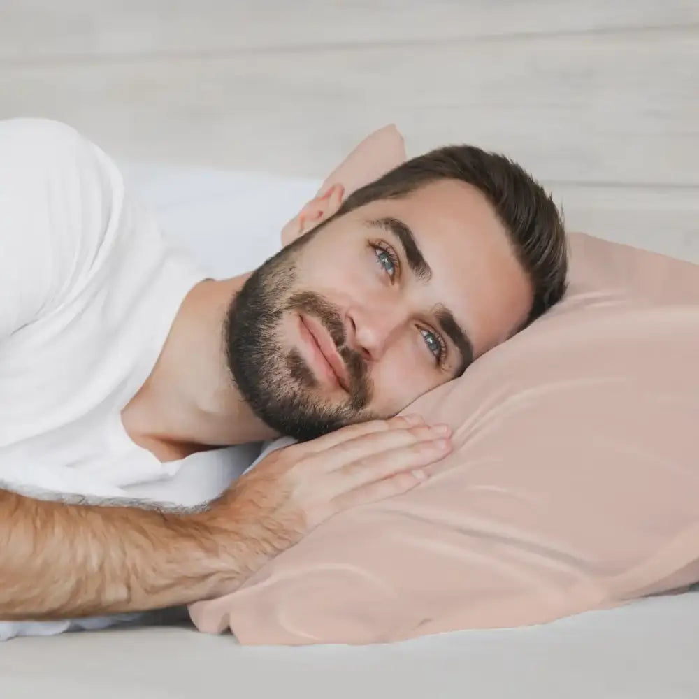 Mann ruht auf einem Seidenkissenbezug Rose Gold in einem stilvollen Schlafzimmer