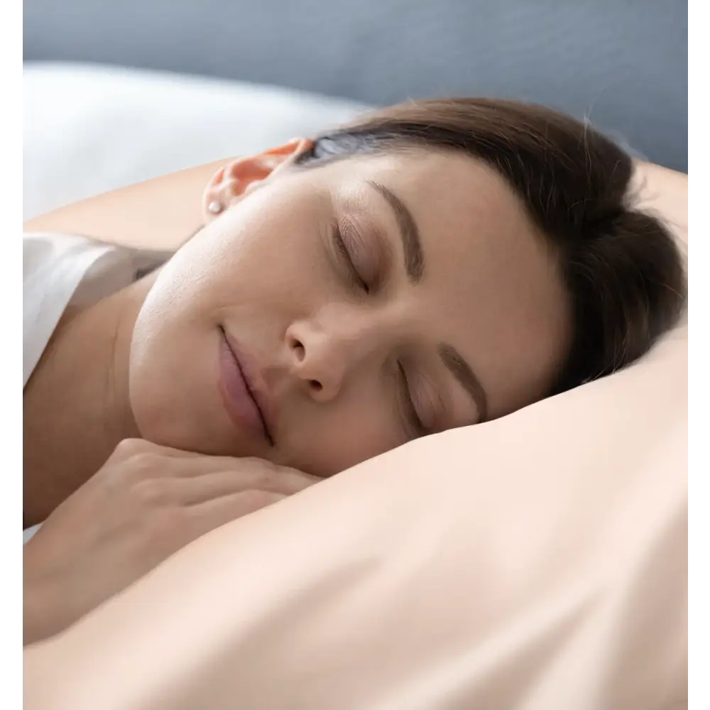Schlafende Frau mit Seidenkissenbezug Rose Gold auf gemütlichem Bett
