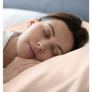 Schlafende Frau mit Seidenkissenbezug Rose Gold auf gemütlichem Bett