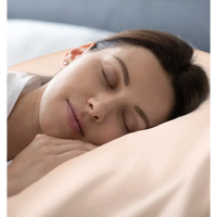 Schlafende Frau mit Seidenkissenbezug Rose Gold auf gemütlichem Bett