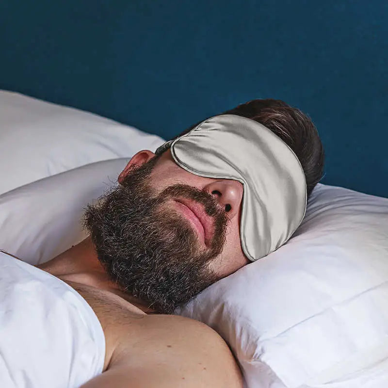 Schlafender Mann mit Weisse Schlaf-Seidenmaske in dunklem Raum